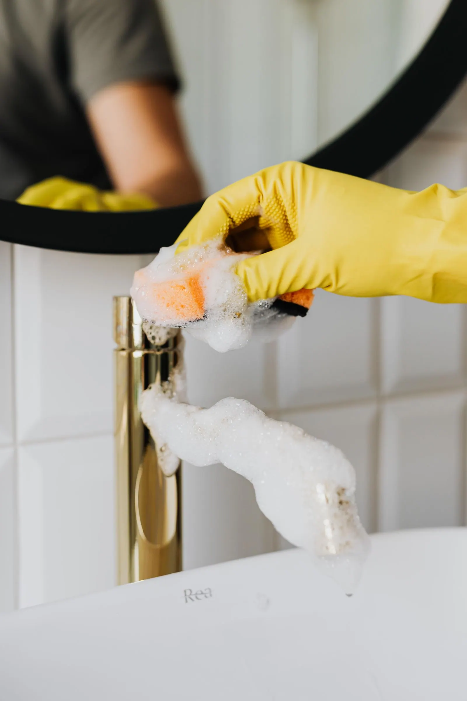 Gloved cleaner deep-cleaning a brass bathroom tap